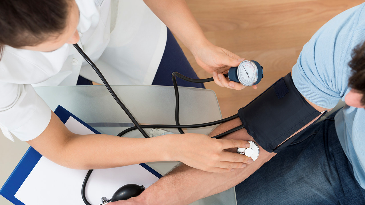 Close-up Of Female Doctor Checking Blood Pressure Of Male Patient