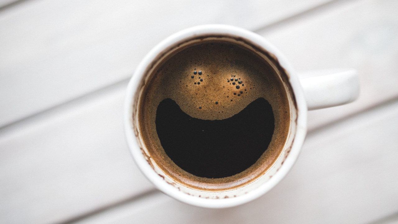 En kaffekopp der skummet er formet slik at det ser ut som et smilefjes.